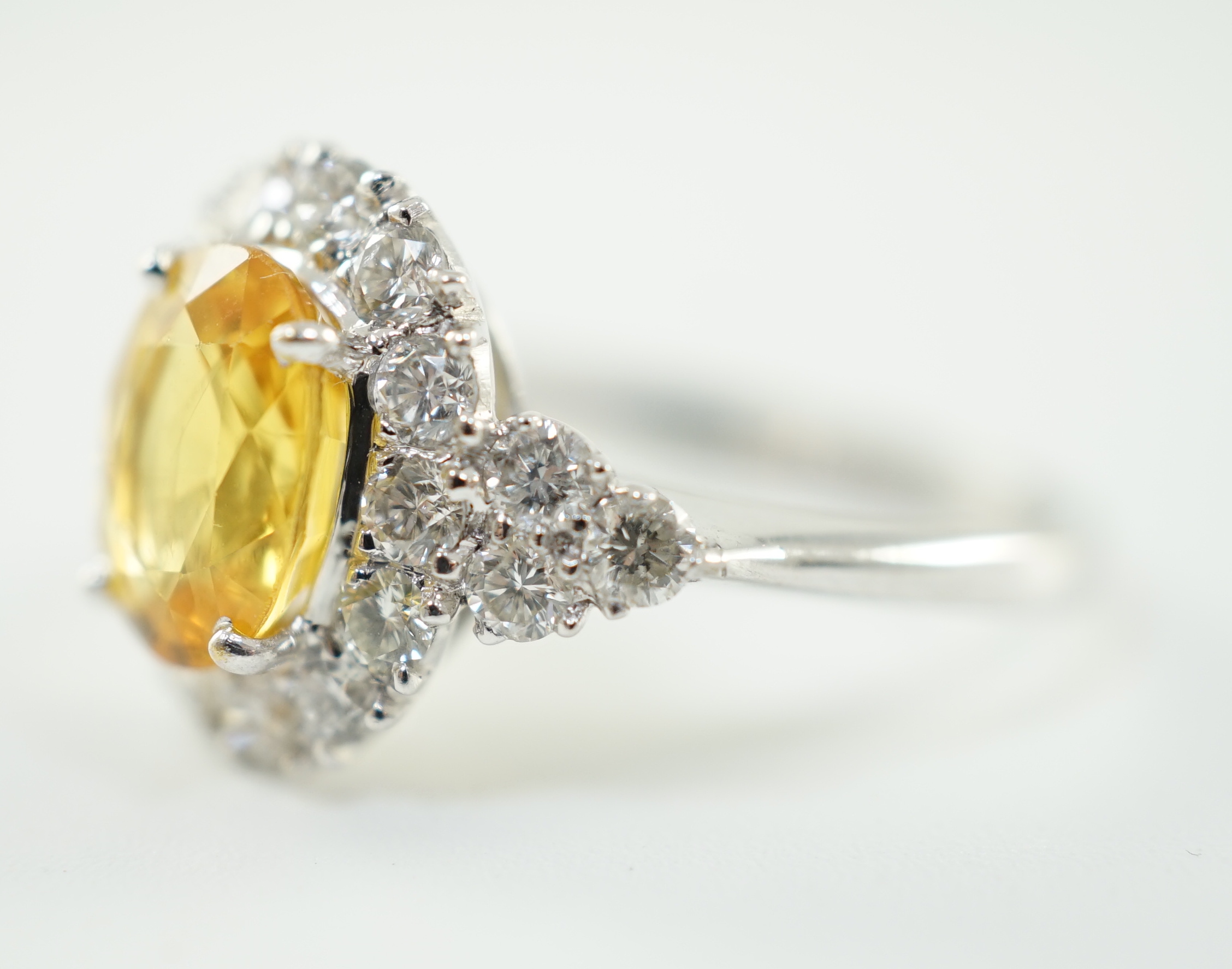 A modern 18ct white gold and single oval cut yellow sapphire set ring